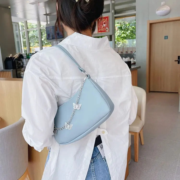Léa – pu schoudertas met vlinderdetail en zilverkleurige ketting